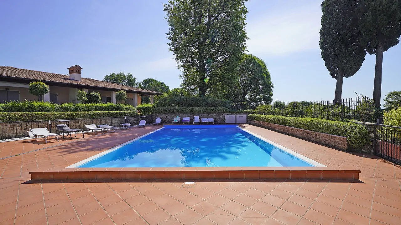 Piscina con bordo in mattoni e sdraio intorno