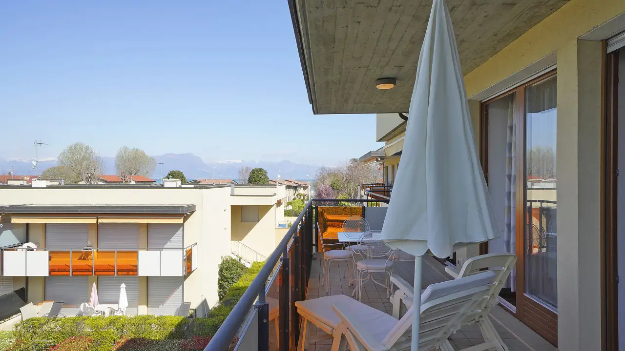 Terrace with table, chairs and umbrella overlooking buildings and mountains