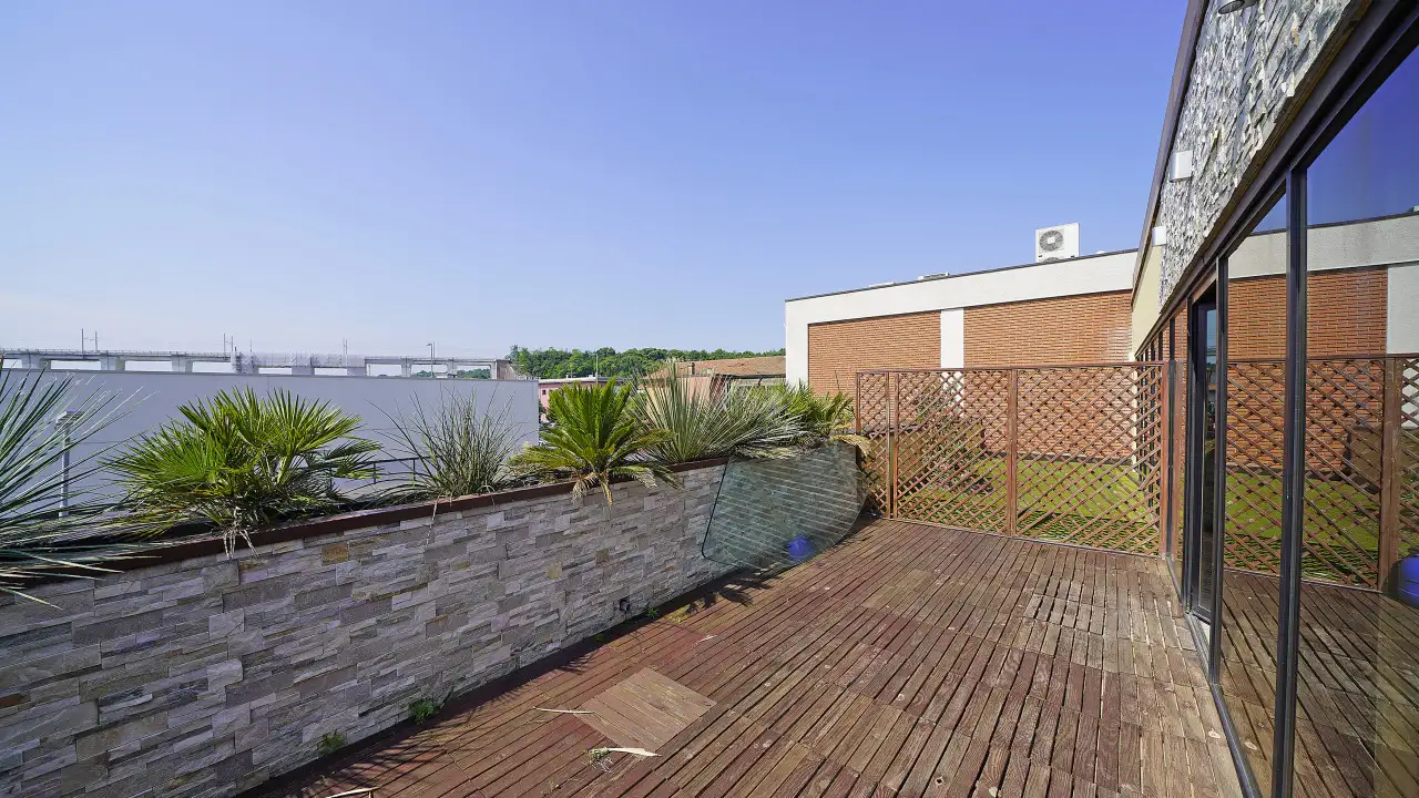 Terrazza con pavimento in legno e ringhiera in pietra e vetro
