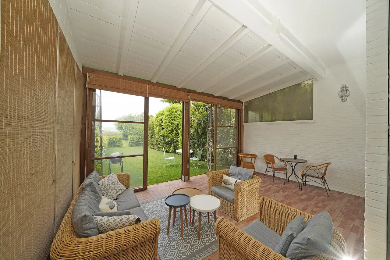 Wohnzimmer mit Korbsesseln und Glastür zum Garten