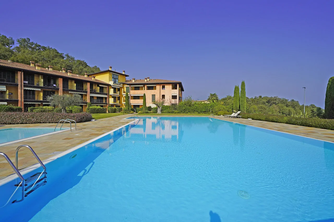 Piscina esterna con acqua limpida e edificio residenziale sullo sfondo