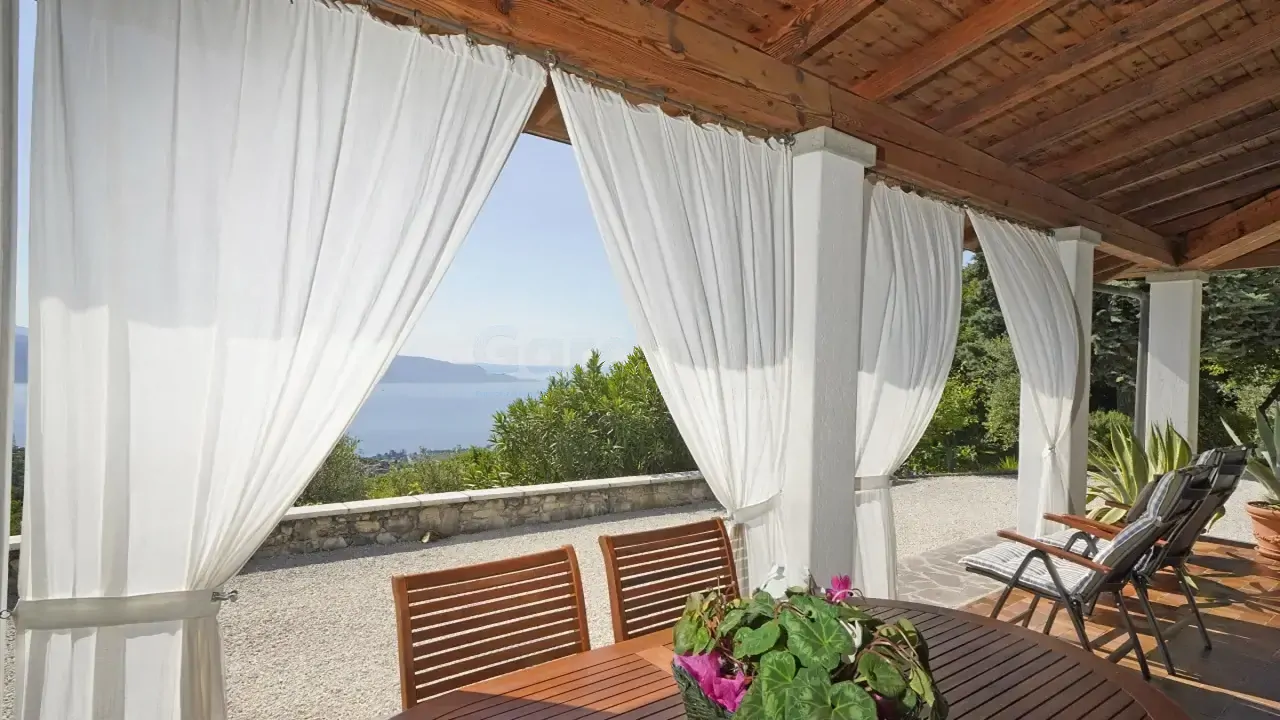 Terrazza coperta con tende bianche e vista sul lago