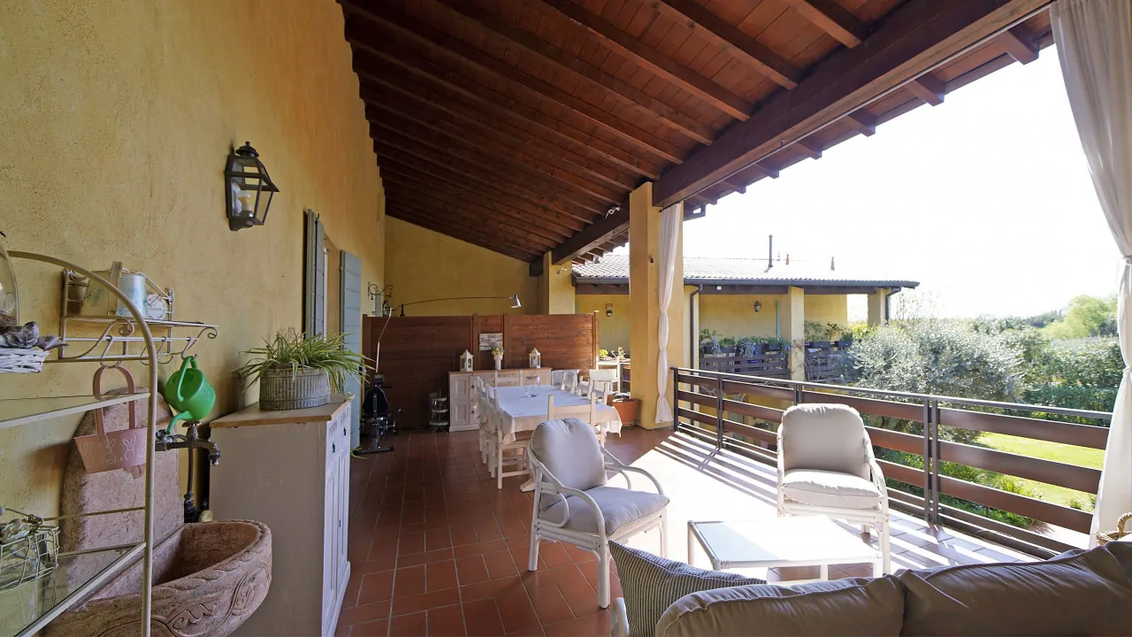 Überdachte Terrasse mit Gartenmöbeln und Blick auf den Garten
