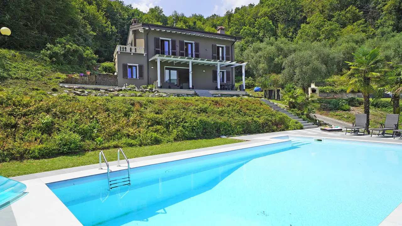 Swimming pool with villa and garden in the background
