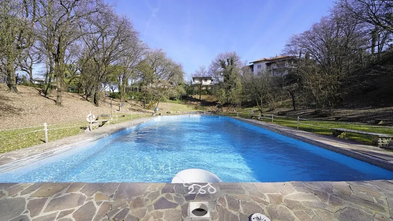 Outdoor swimming pool with clear water and surrounding green area