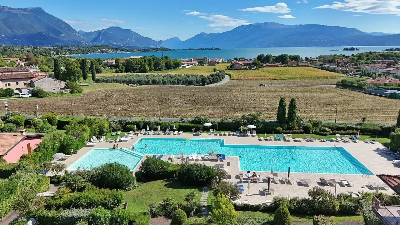 Außenpool mit Rasen und Seeblick im Hintergrund in Manerba del Garda