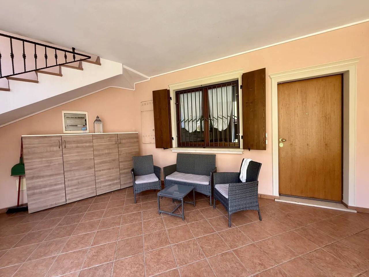 Porch with garden furniture and cabinet under the stairs