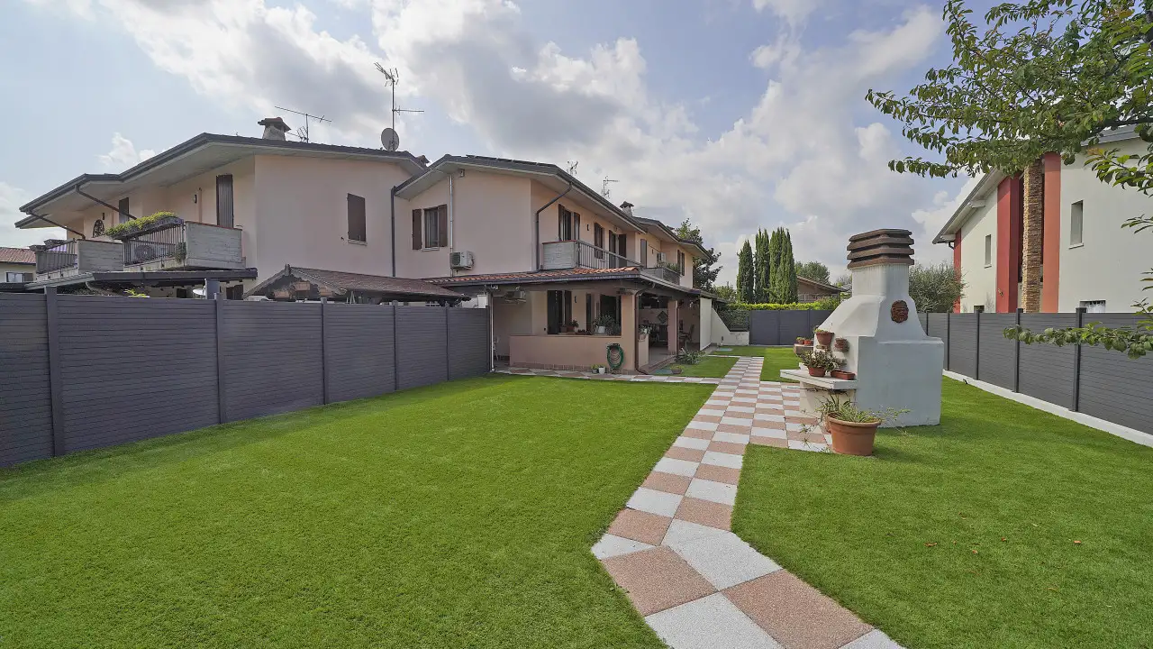 Giardino con prato e camminamento piastrellato davanti a villa a Sirmione