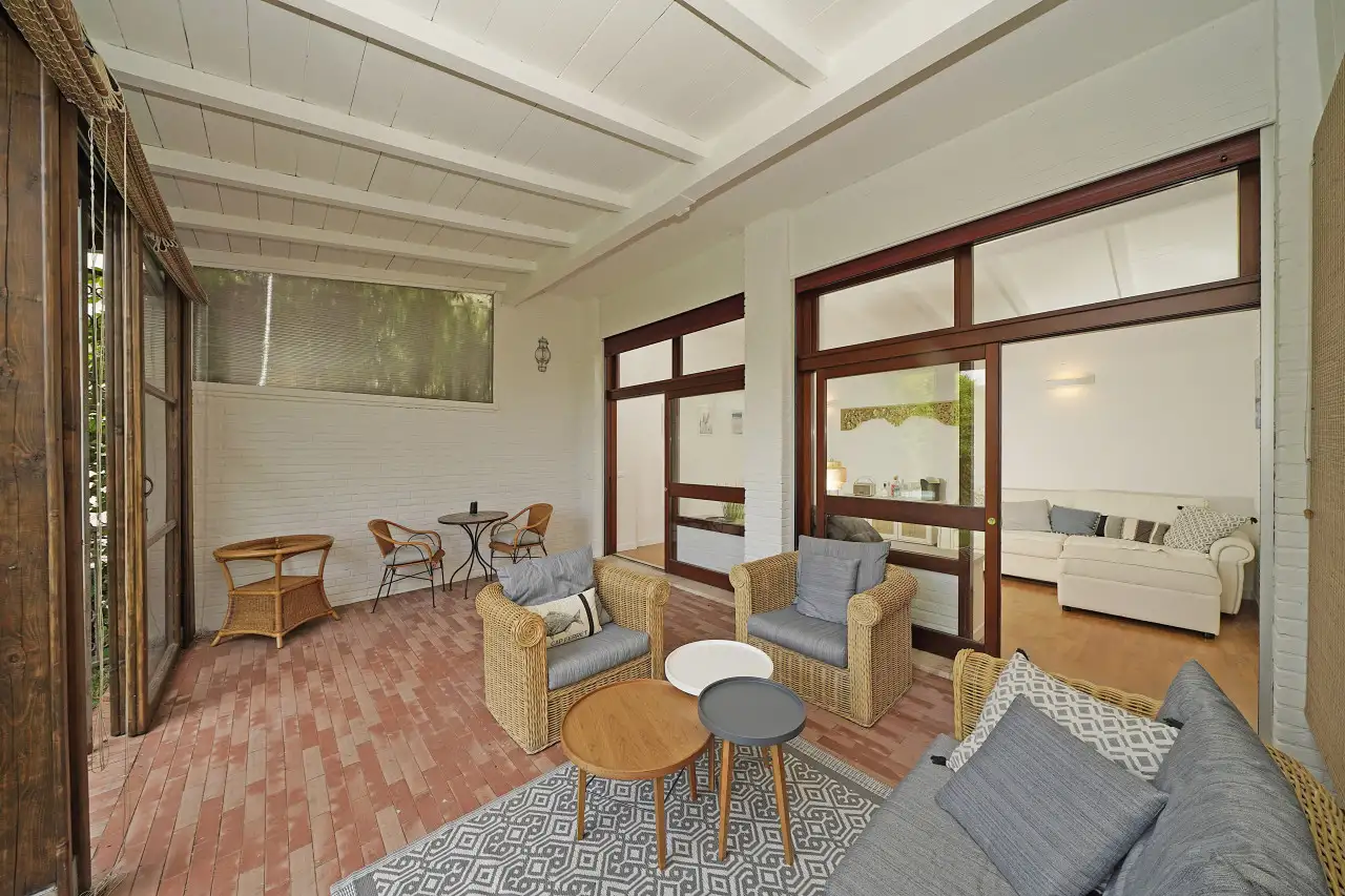 Überdachte Terrasse mit Korbmöbeln und kleinen Tischen