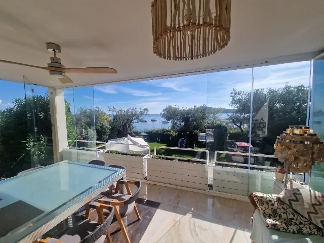 Terrazza con tavolo e vista lago attraverso vetrate scorrevoli