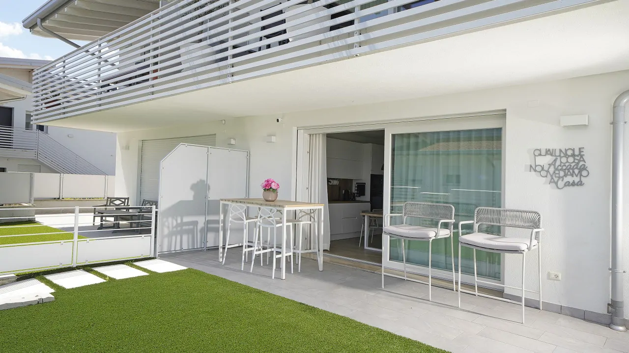 Exterior with high table and chairs on synthetic grass in front of sliding entrance