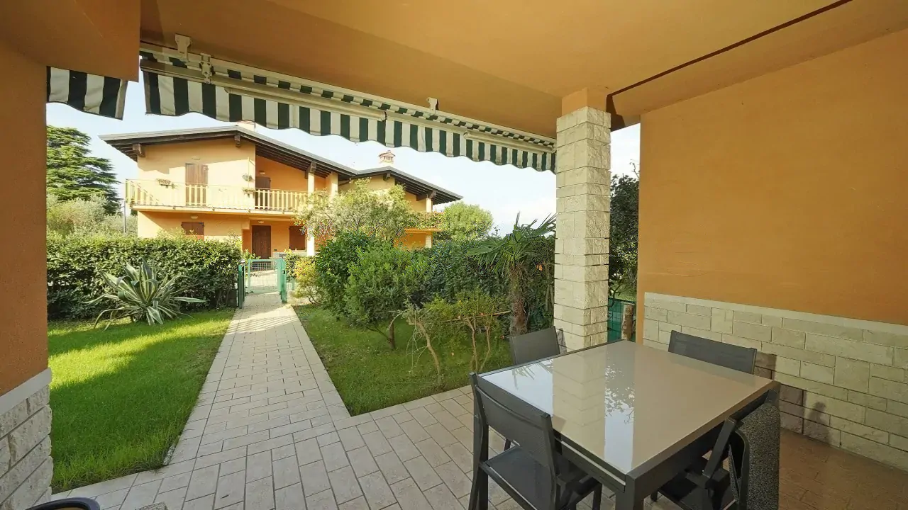 Portico con tavolo e sedie e vista sul giardino e casa vicina