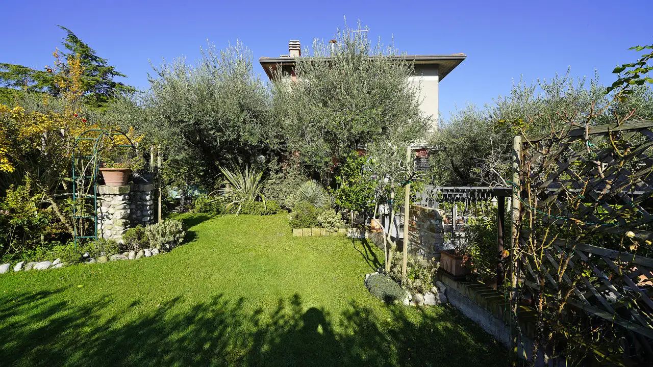 Giardino con prato e piante varie davanti alla villa