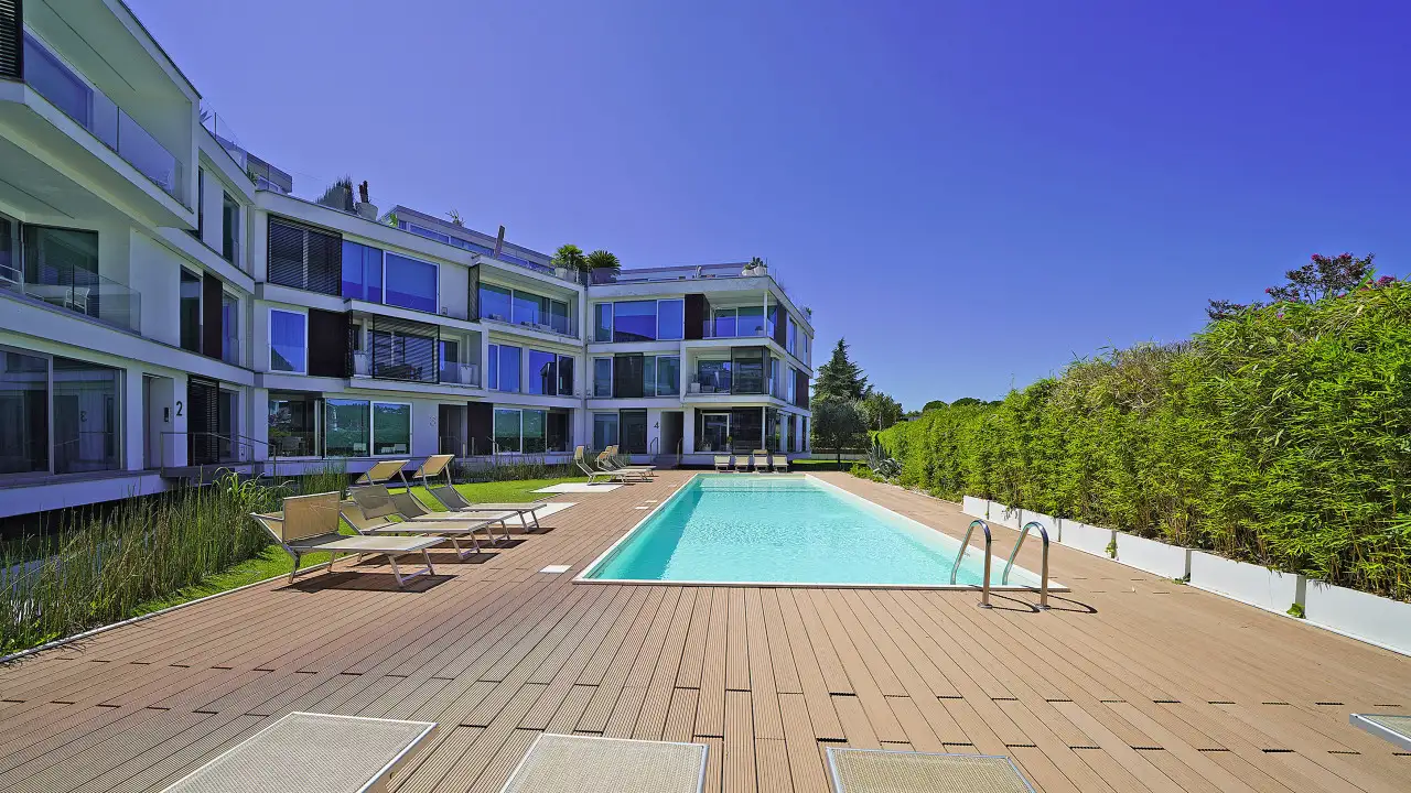 Piscina esterna con lettini e edificio residenziale sullo sfondo