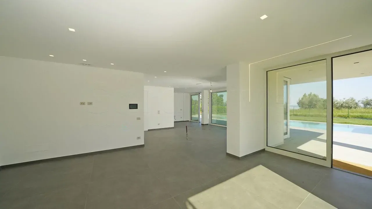 Großes Wohnzimmer mit großen Fenstern und Blick auf Pool und Garten