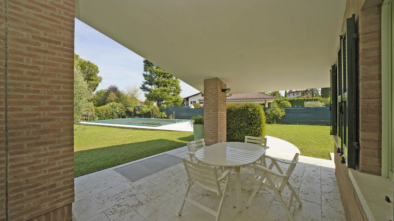 Veranda mit Tisch und Stühlen mit Blick auf Garten und Pool