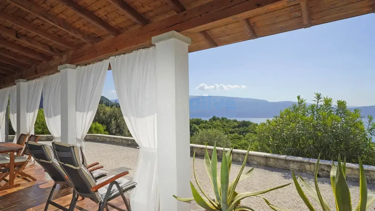 Covered terrace with deck chairs and view of lake and mountains