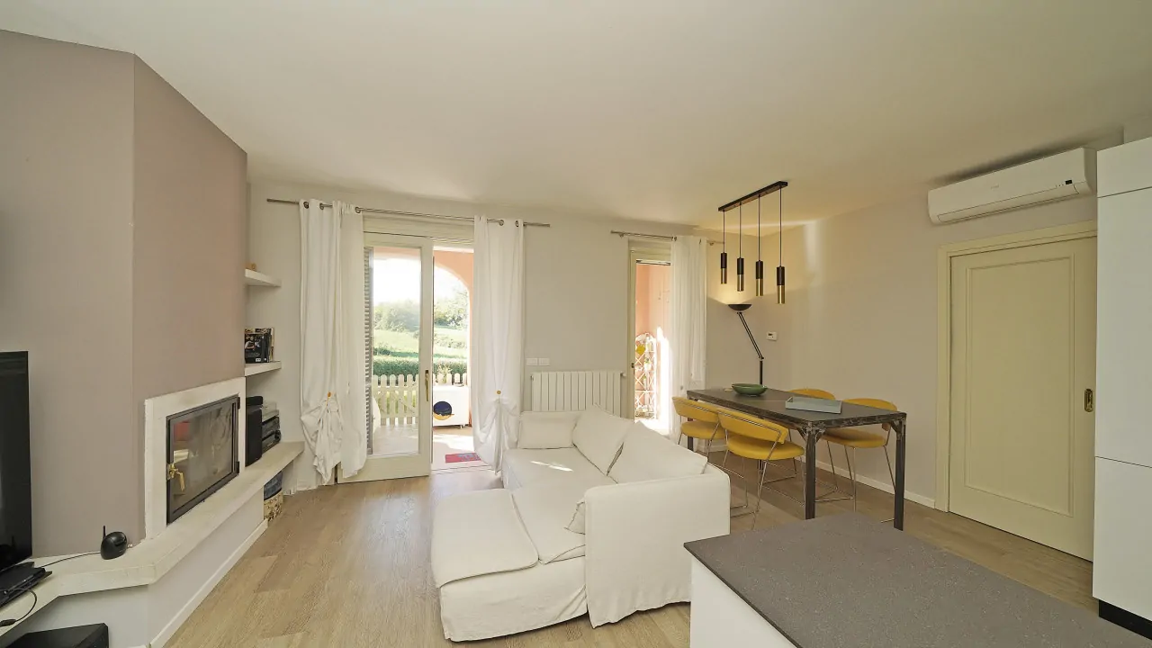 Wohnzimmer mit weißem Sofa, Kamin und Esstisch mit gelben Stühlen