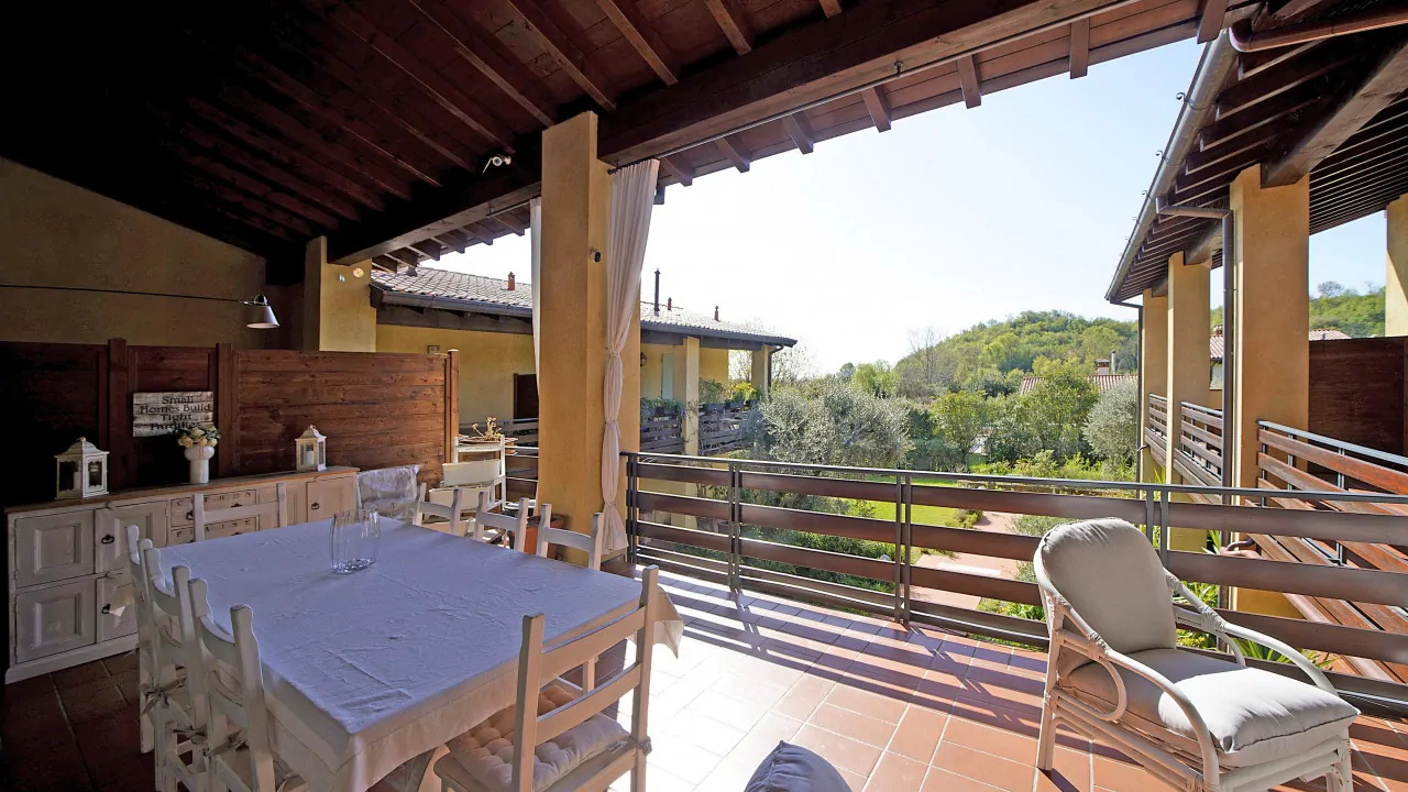 Überdachte Terrasse mit Esstisch und Holzstühlen