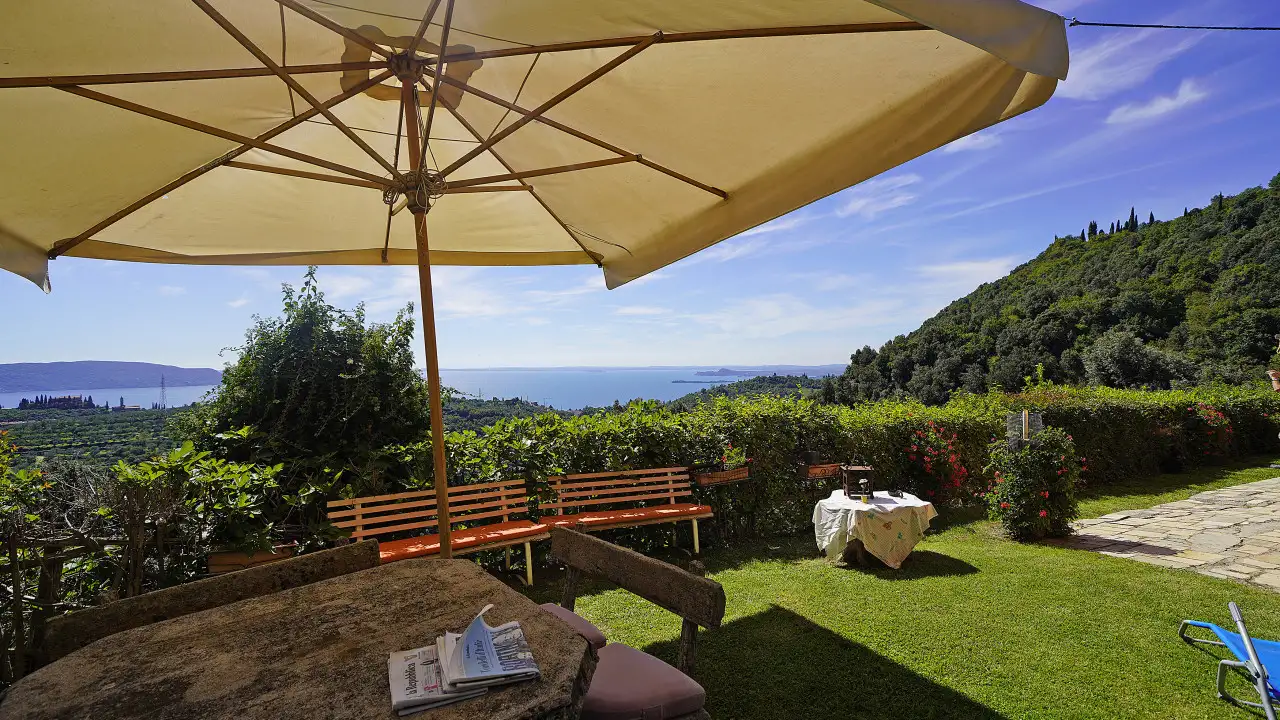 Giardino con tavolo, ombrellone e vista lago
