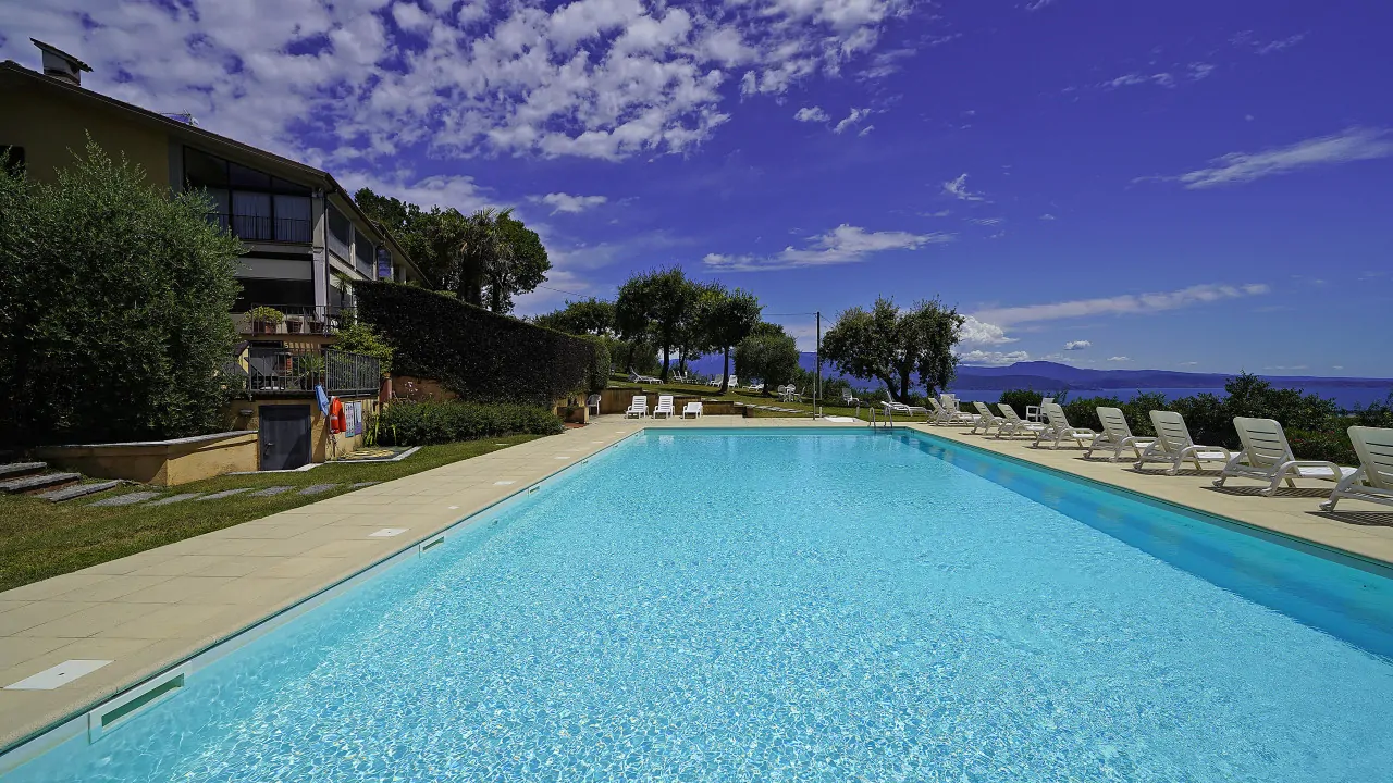 Piscina con sdraio e vista sul lago e cielo nuvoloso