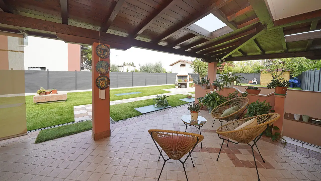 Veranda mit Stühlen und Blick auf Garten mit Grill