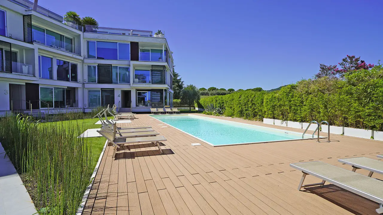 Swimming pool with sun loungers and modern building in the background