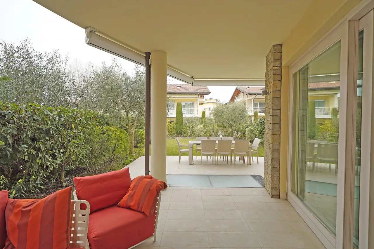 Porch with red sofa and outdoor dining table in the garden