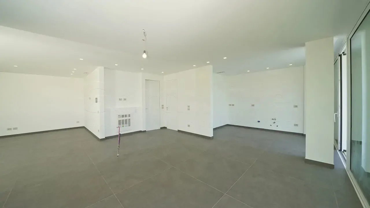 Leeres Wohnzimmer mit grauem Fliesenboden und weißen Wänden