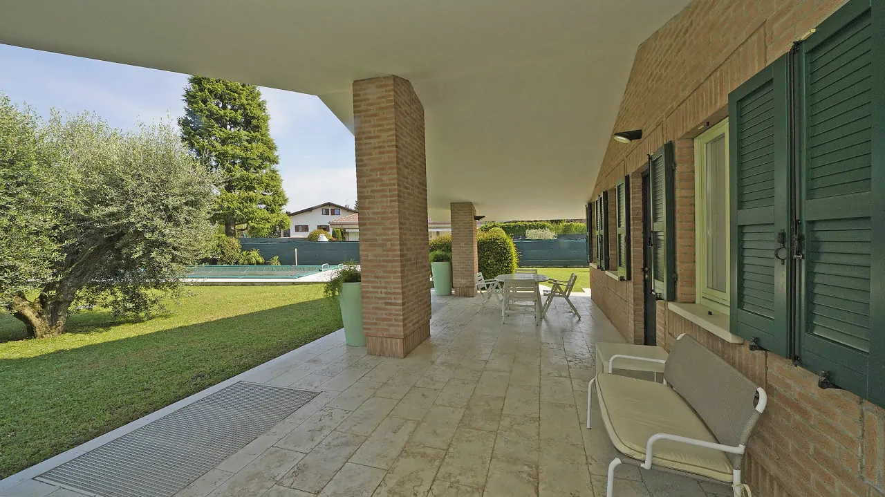 Veranda mit Steinboden und Blick auf Garten mit Schwimmbad
