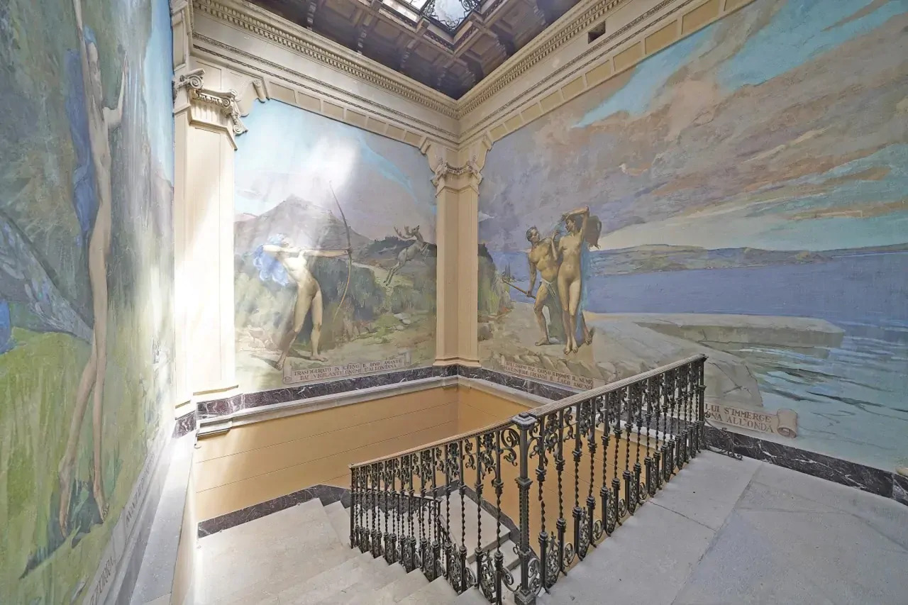 Treppe mit Schmiedeeisengeländer und Fresken an den Wänden