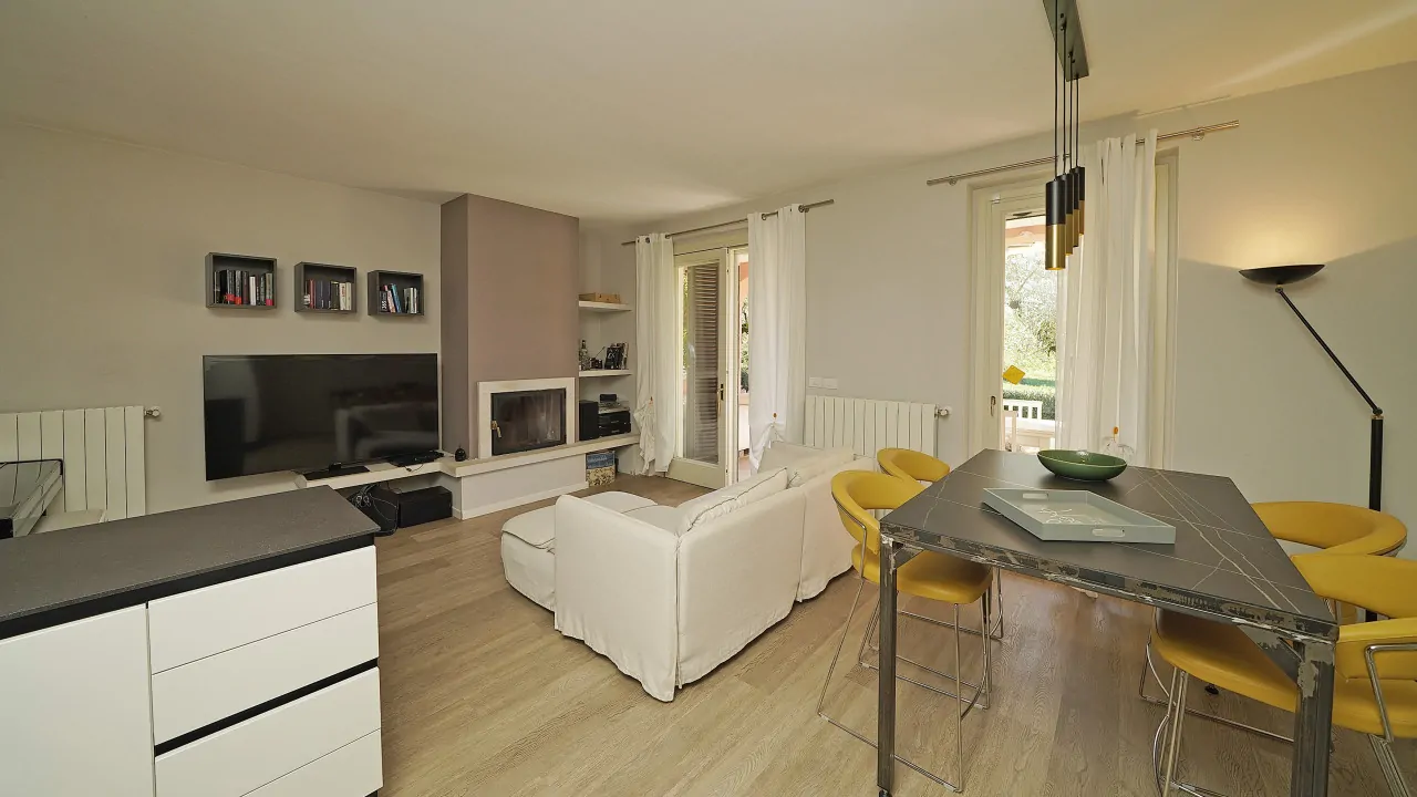 Wohnzimmer mit weißem Sofa, Kamin und Esstisch mit gelben Stühlen