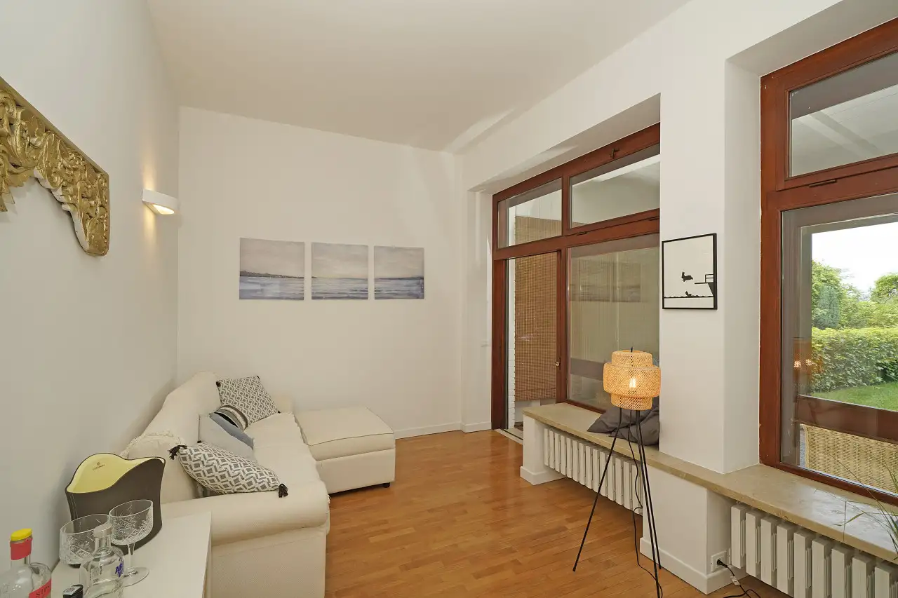 Living room with white sofa and large windows overlooking the garden