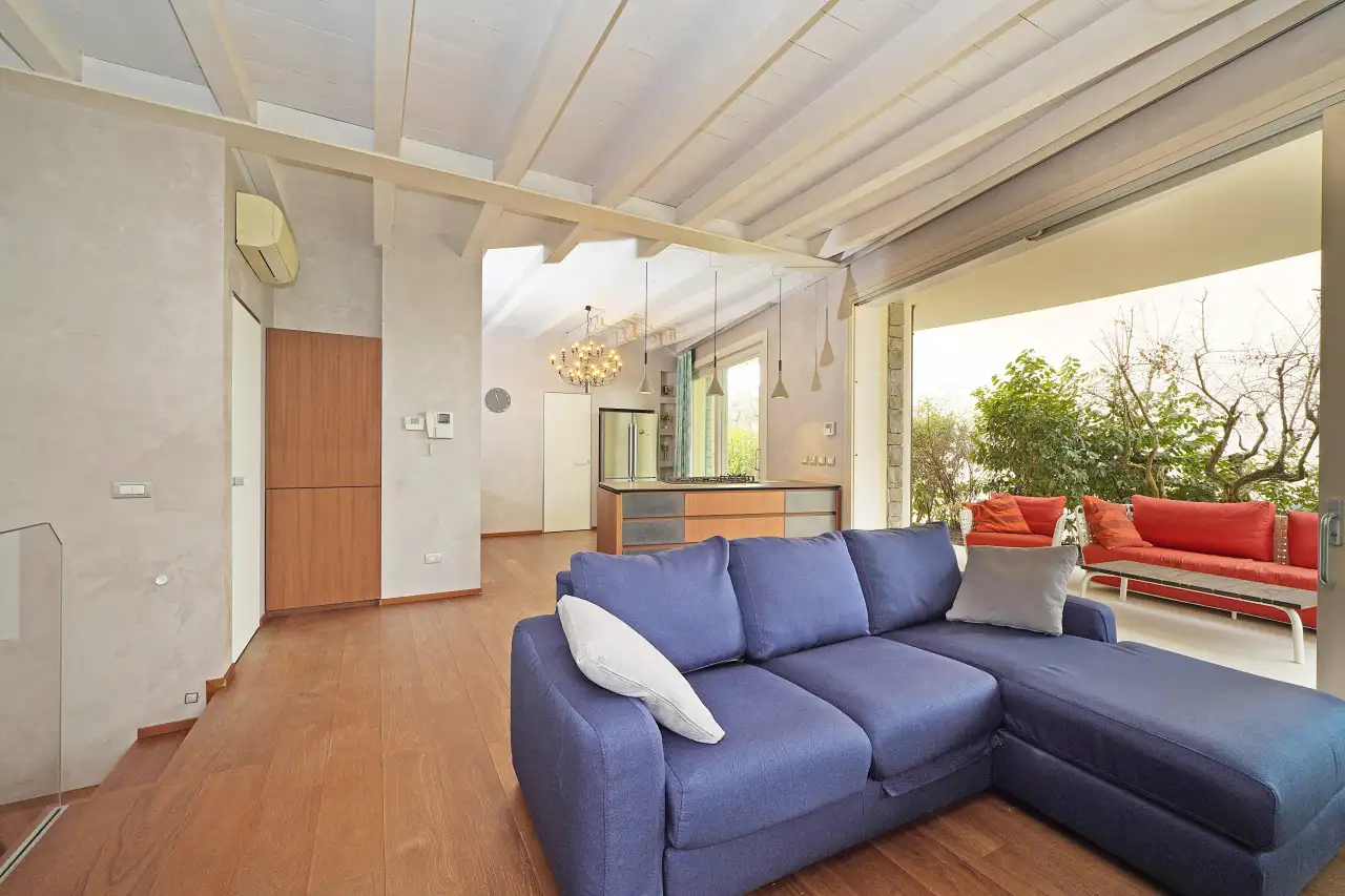 Living room with blue sofa and opening to terrace with red sofas