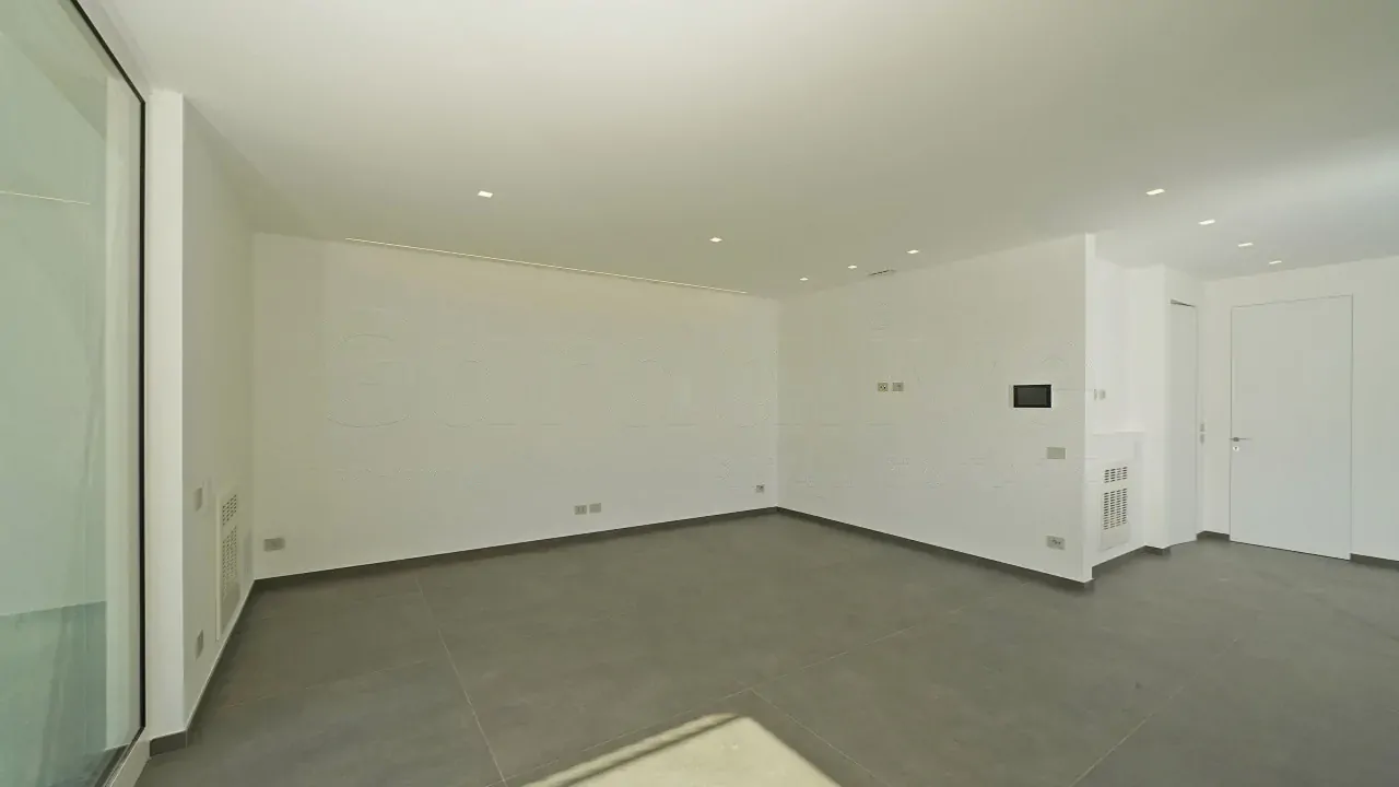 Leeres Wohnzimmer mit weißen Wänden und grauem Boden