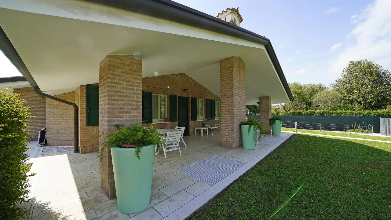 Veranda mit Backsteinsäulen und grünen Töpfen
