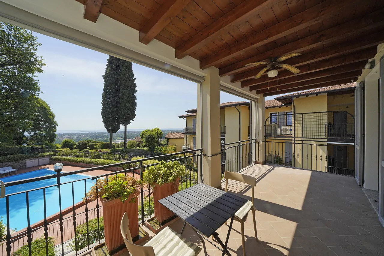 Überdachte Terrasse mit Tisch, Stühlen und Blick auf den Pool und die Landschaft