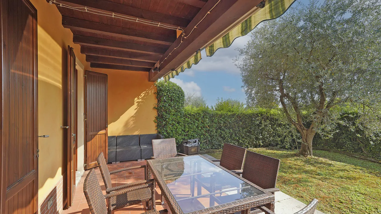 Giardino privato con tavolo e sedie sotto portico coperto