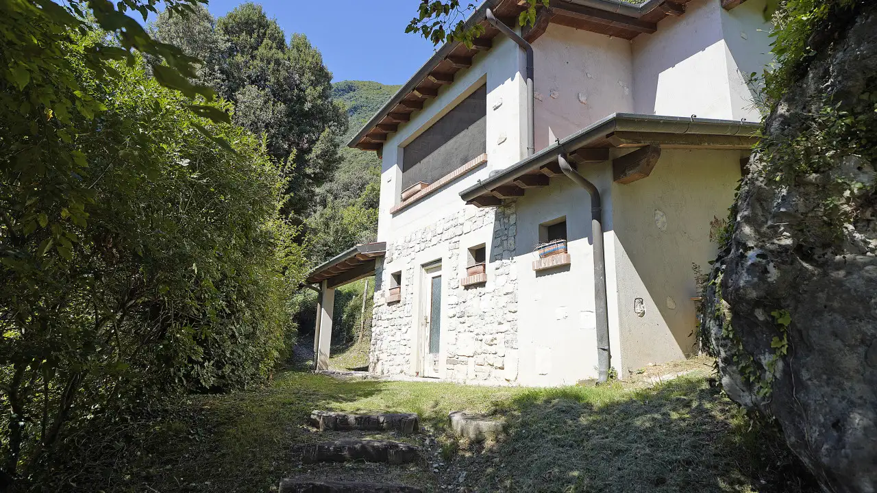 Esterno della casa con parete in pietra e scala in giardino