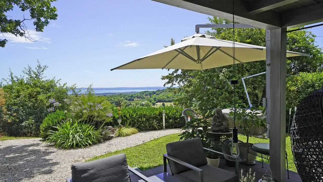 Garten mit Stühlen und Sonnenschirm mit Seeblick und Vegetation