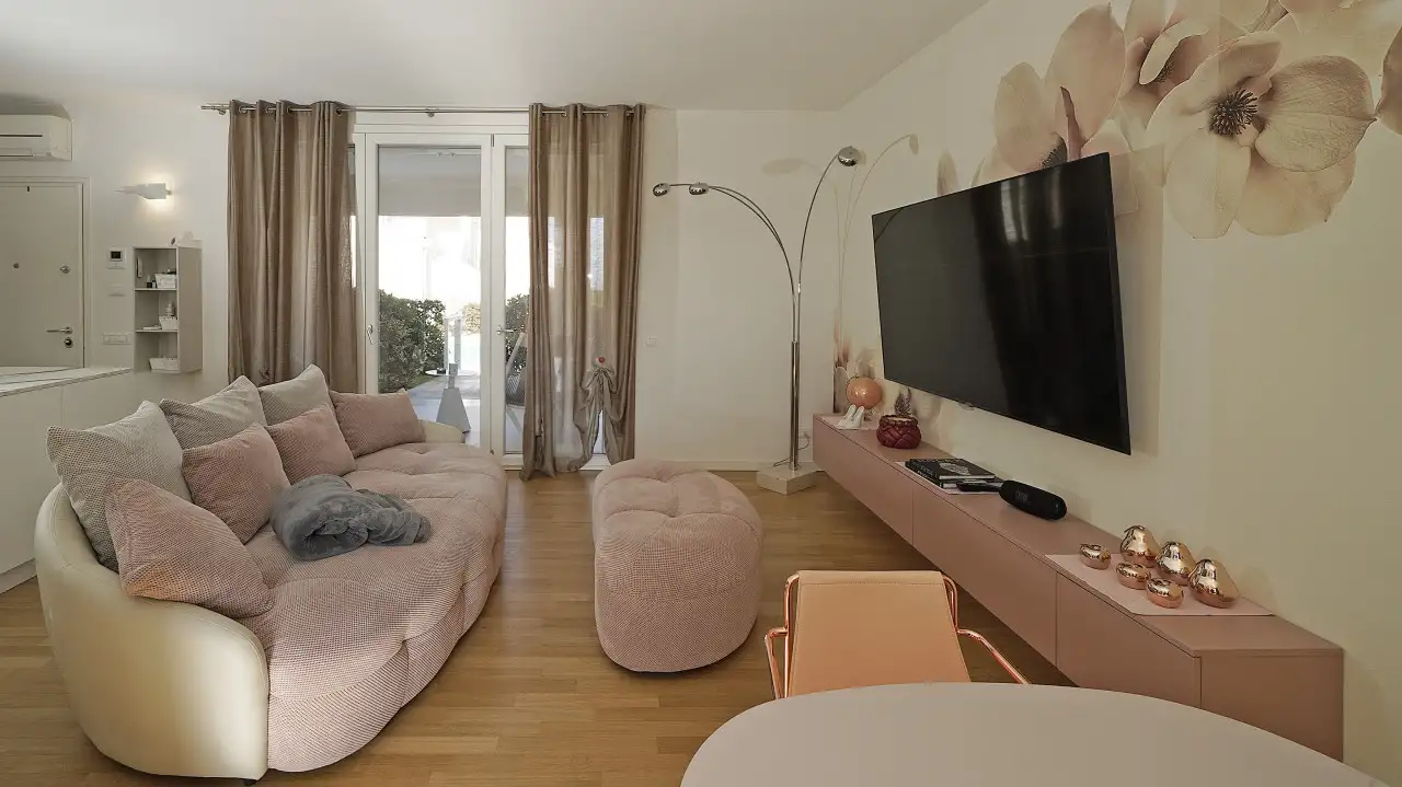 Wohnzimmer mit rosa Sofa und wandmontiertem TV-Schrank