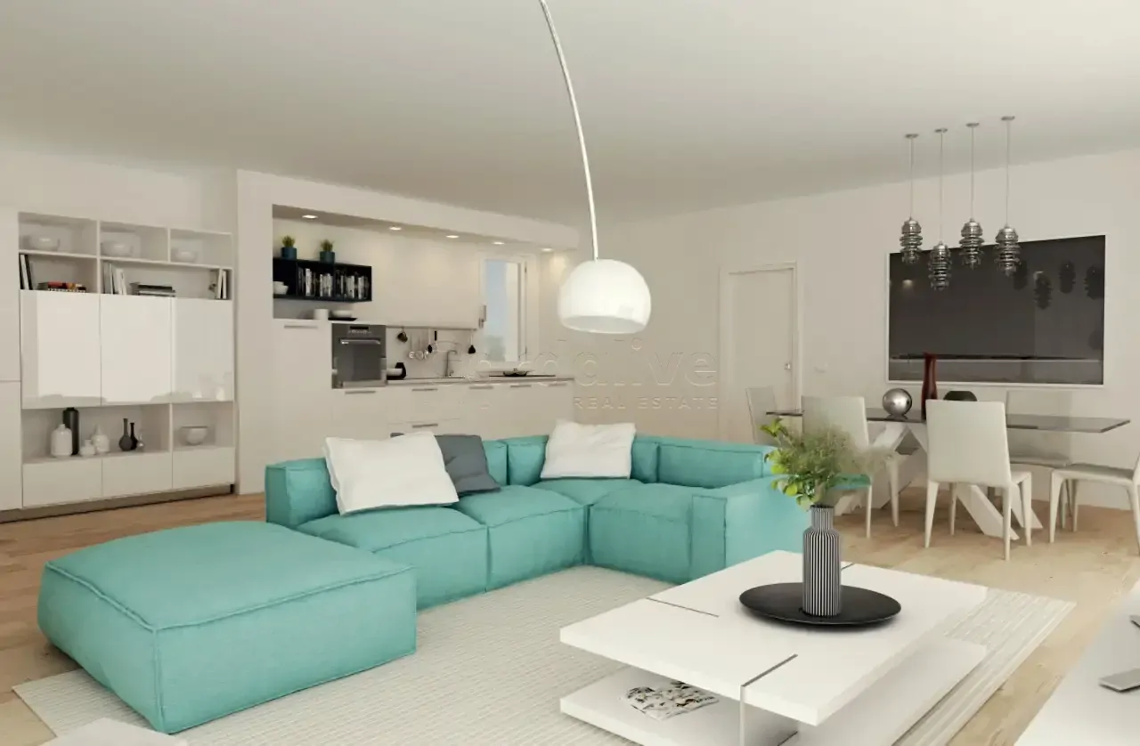 Wohnzimmer mit türkisfarbenem Ecksofa und weißer offener Küche