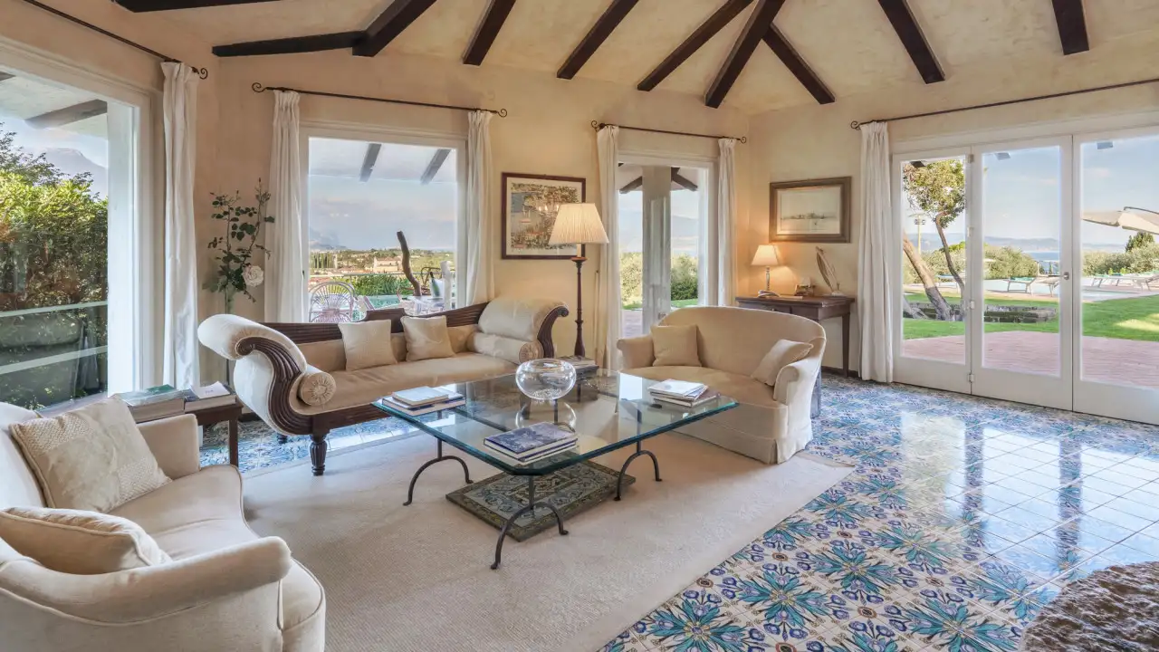 Wohnzimmer mit Sofas und Glastisch vor großen Fenstern