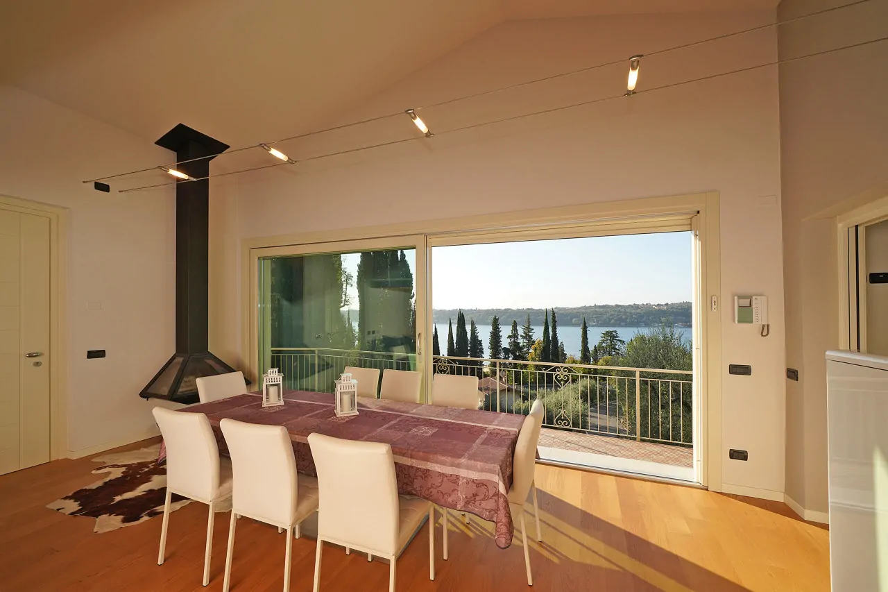 Wohnzimmer mit Esstisch und Seeblick durch große Schiebetüren