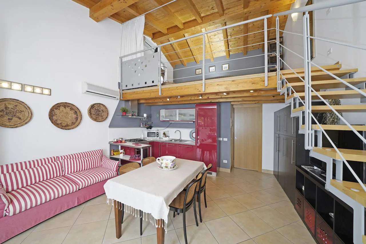 Living room with red and white striped sofa and red open kitchen