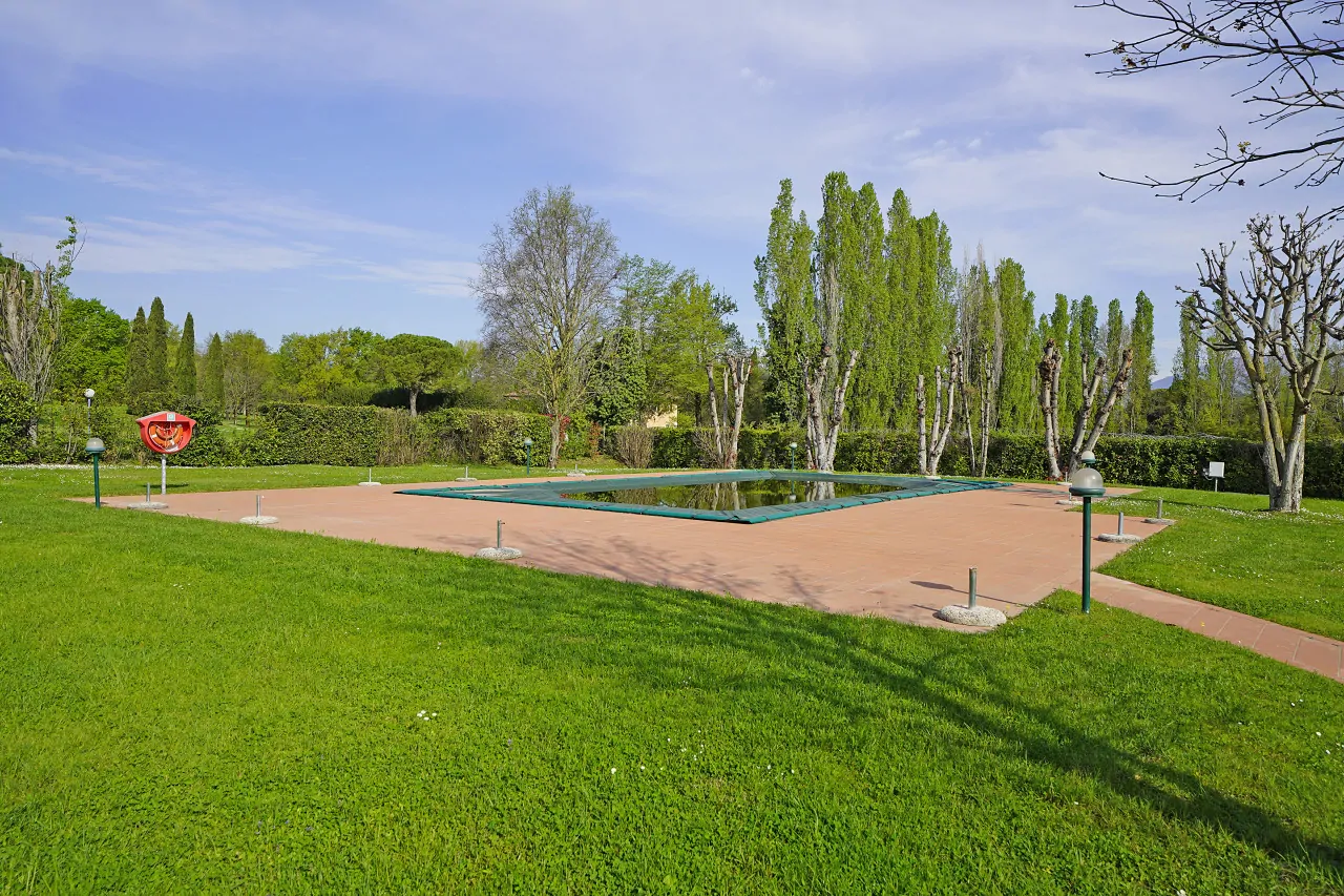 Piscina rettangolare con bordo in cemento e prato verde circostante