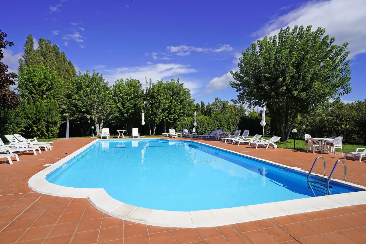 Piscina rettangolare con bordo bianco e sdraio intorno