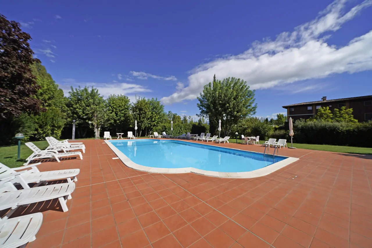 Piscina all'aperto con lettini e ombrelloni su pavimentazione in cotto