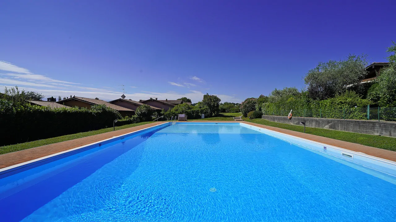 Piscina rettangolare all'aperto con bordo in mattoni e prato circostante
