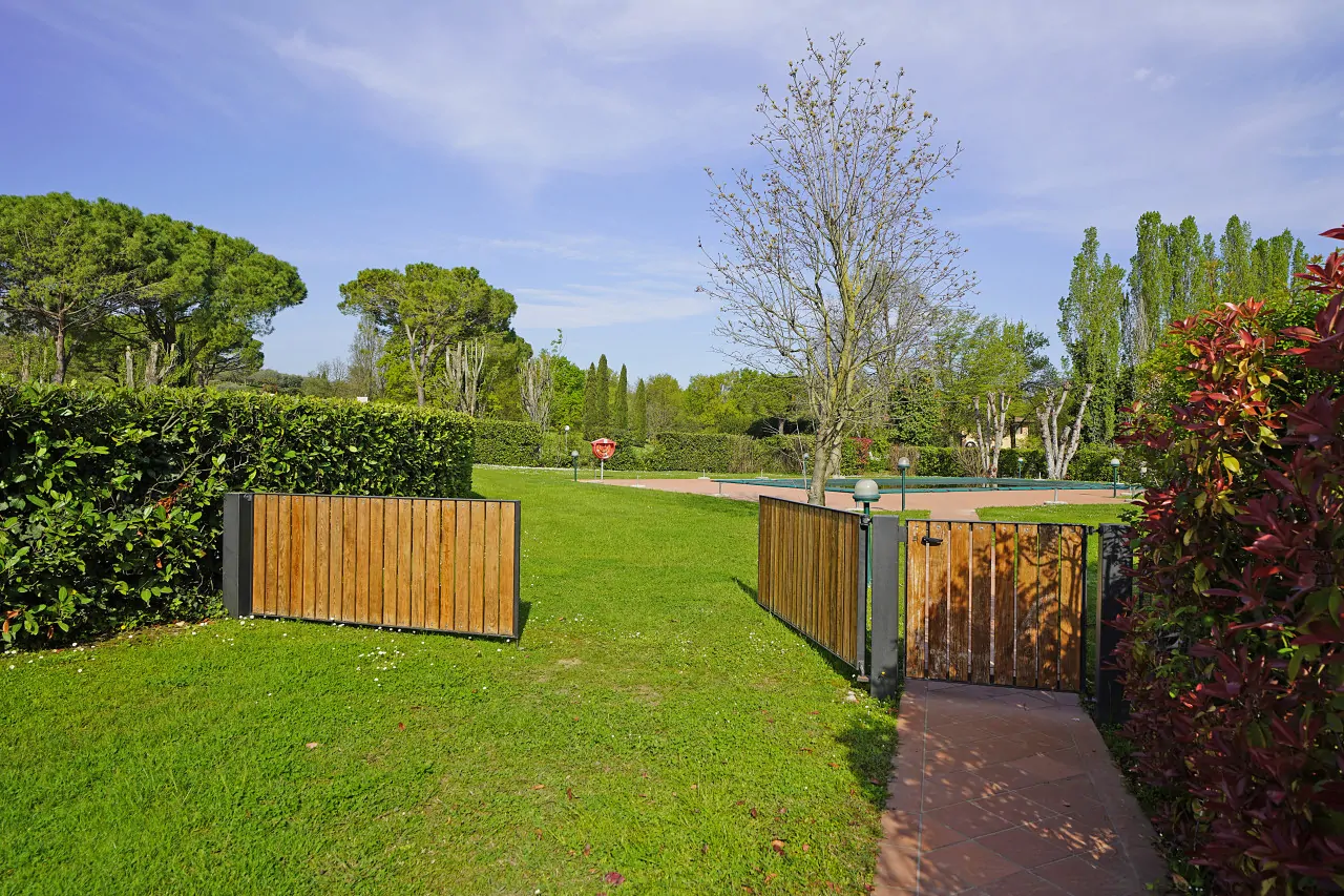 Garden entrance with wooden gate and green lawn